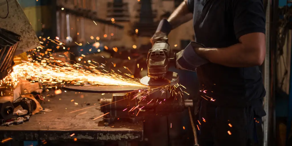 Man working with metal fabrication tools, with sparks flying.